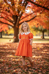 Orange smocked dress with embroidered pumpkin. DRG64521 AMY